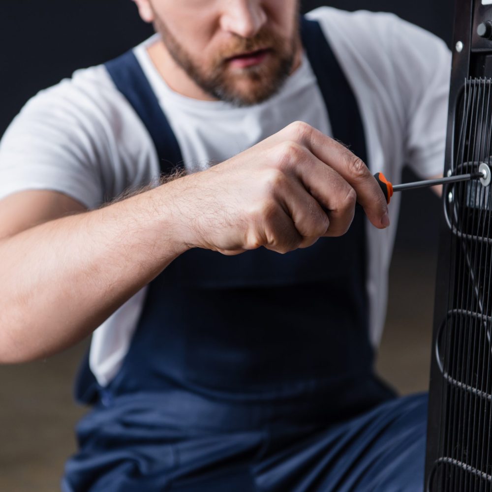 cropped shot of male craftsman repairing water cooler with screwdriver