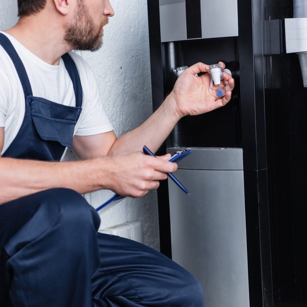 cropped shot of male repairman with clipboard checking broken water cooler